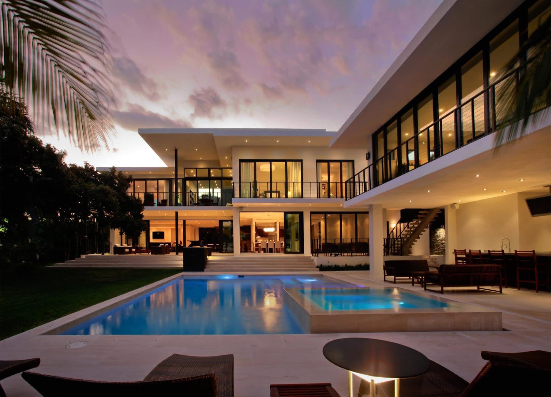 Modern Miami home lit at dusk with pool and spa